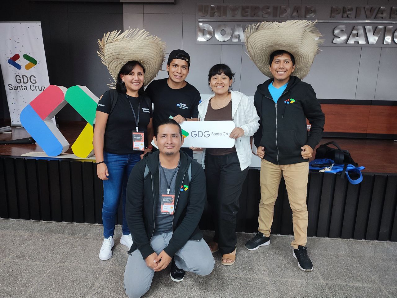 Community team posing with the GDG Santa Cruz sign at the venue entrance